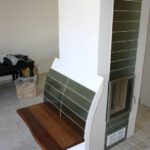 Moderner Säulen-Kachelofen mit wärmender Sitzbank